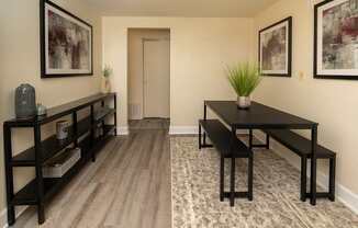 A black table with a plant on it sits in the middle of a room with a wooden floor and a carpet.