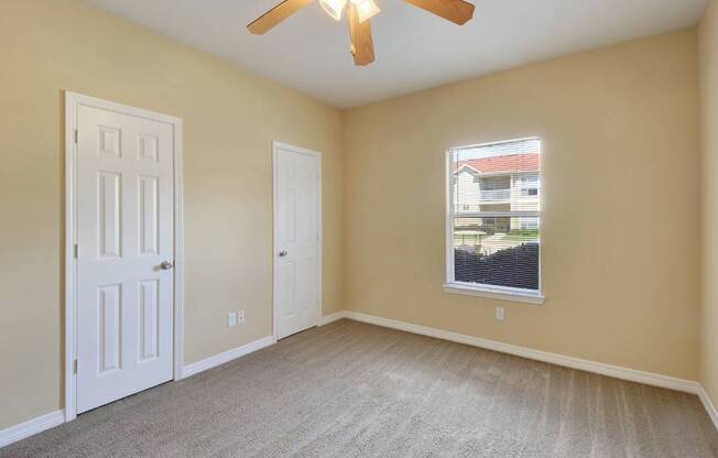 A room with a ceiling fan and a window with blinds.