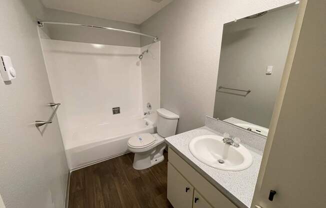 A small bathroom with a toilet, sink, and shower.