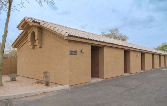 a tan building with three doors and a sidewalk