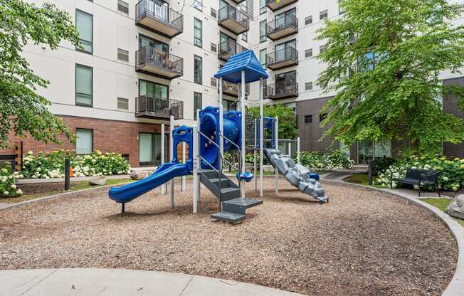 A playground with a blue slide and a white railing.