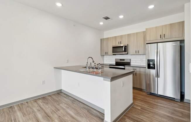 a kitchen with a large island and a stainless steel refrigerator at The Depot in The Depot Raymore, MO 64083