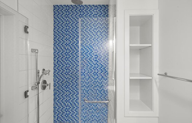 A white bathroom with a blue tiled shower.