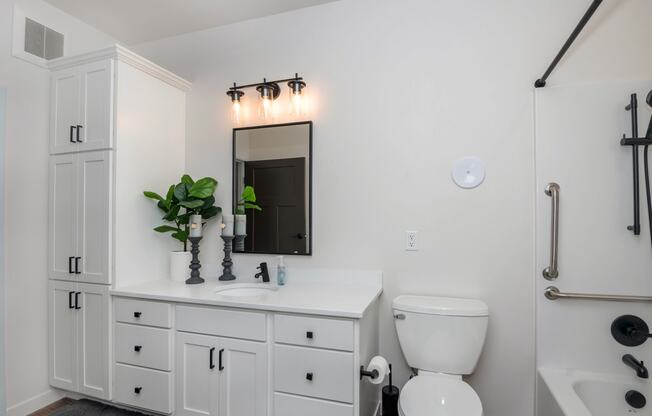 a bathroom with white cabinets and a white toilet and sink at The Crossings at Windsong, Prescott Valley, AZ