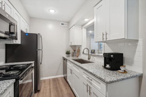 a kitchen with white cabinets and granite counter tops and a stainless steel refrigerator at Lake Johnson Mews, Raleigh