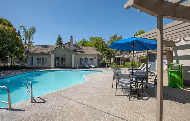 A pool with chairs and umbrellas at Zinfandel Village Apartments, California, 95670
