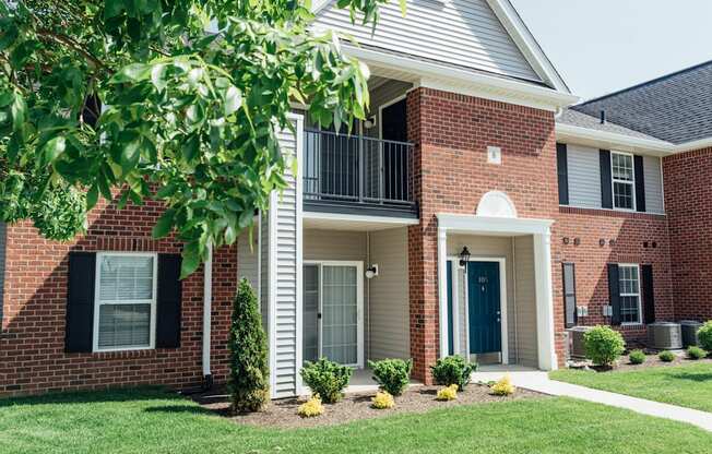 the outlook of a brick house with a balcony and a yard