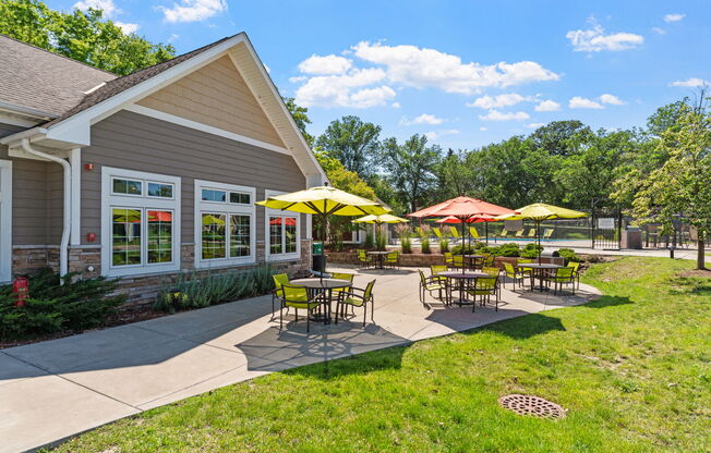 a patio with tables and umbrellas outside of a building