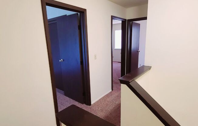 A hallway with a blue door and a mirror on the wall.