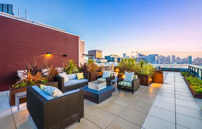 A rooftop patio with a couch, chairs, and plants.
