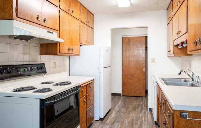 A kitchen with wooden cabinets and a white stove top oven. Fargo, ND Islander Apartments