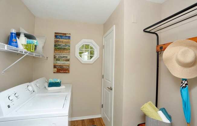 a laundry room with a washing machine and a hat on the wall