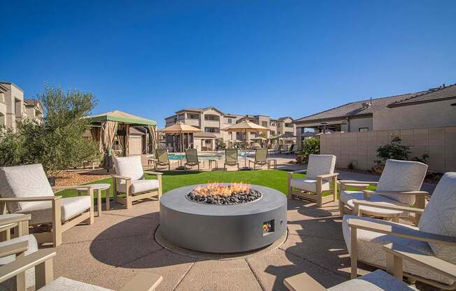 A fire pit sits in the middle of a patio surrounded by chairs.