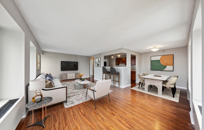 the living room and dining room of a house with wood floors and white furniture