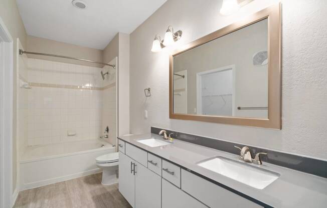 a bathroom with a white tub and a white toilet next to a white sink with a mirror