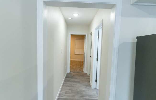an empty hallway with a door to a bathroom and a hall way to a bedroom
