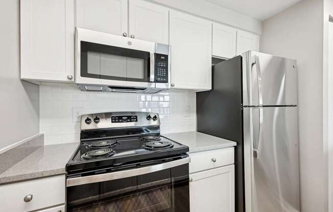 A kitchen with a black refrigerator and a black and silver stove.