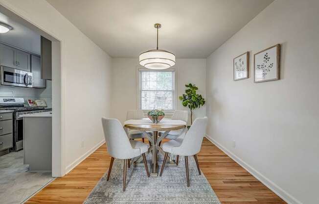 A dining room with a table set for two and a potted plant on the table.
