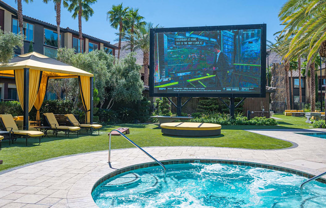 A pool with a water slide and a screen in the background.