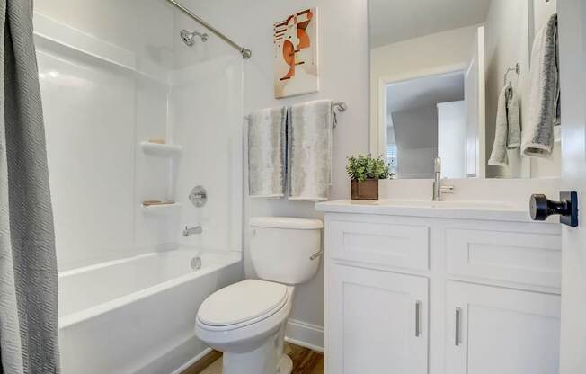 A white bathroom with a toilet, sink, and bathtub.