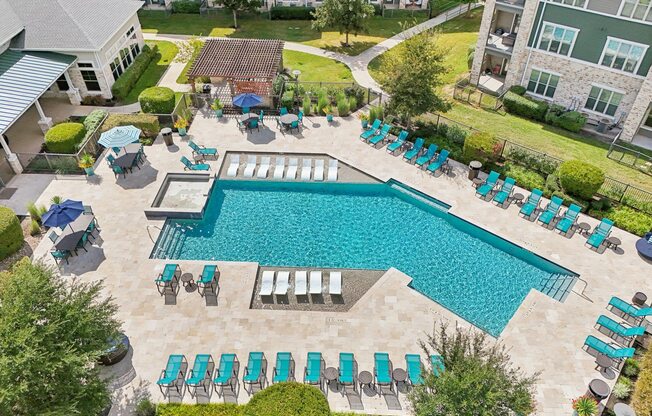 A large swimming pool surrounded by lounge chairs and umbrellas.