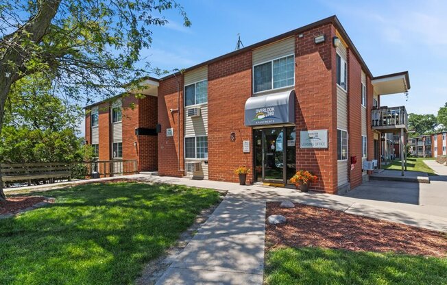 the front of a brick building with a sidewalk and grass