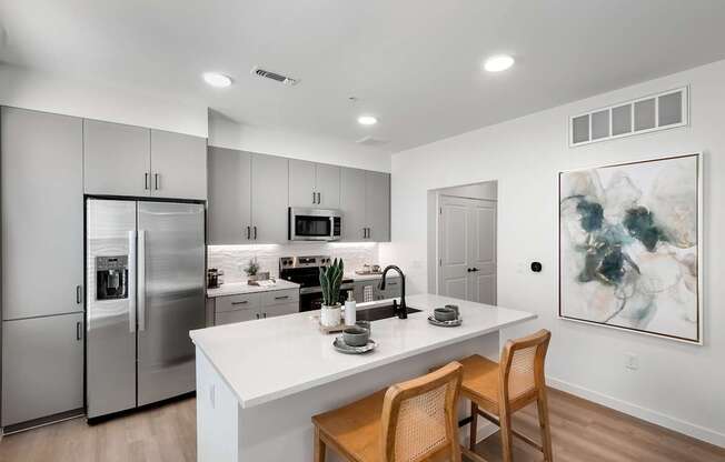 A modern kitchen with a white countertop and stainless steel appliances.