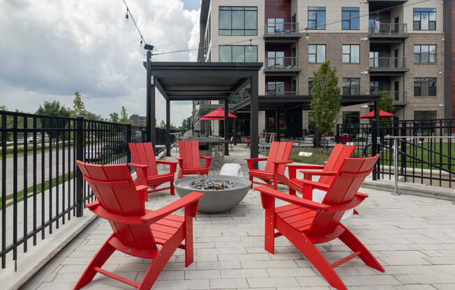 a group of red chairs sitting around a fire pit on a patio