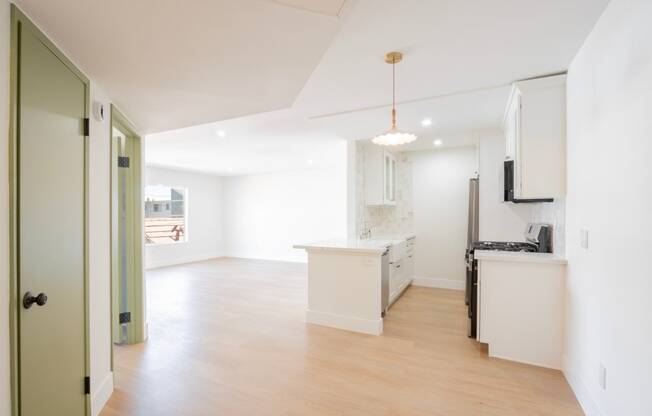 an open kitchen and living room with white walls and wood flooring