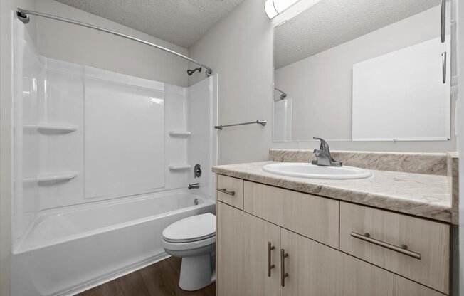 A white bathroom with a toilet, sink, and shower.