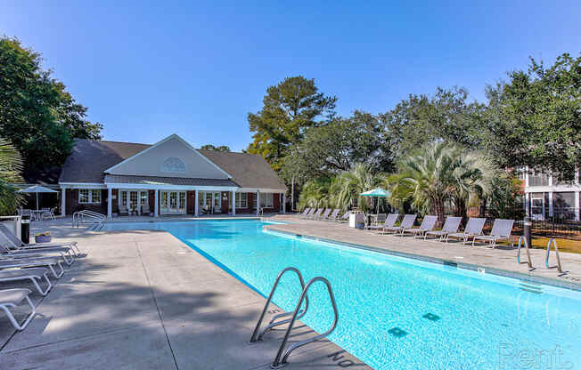 a swimming pool with chairs and a building in the background