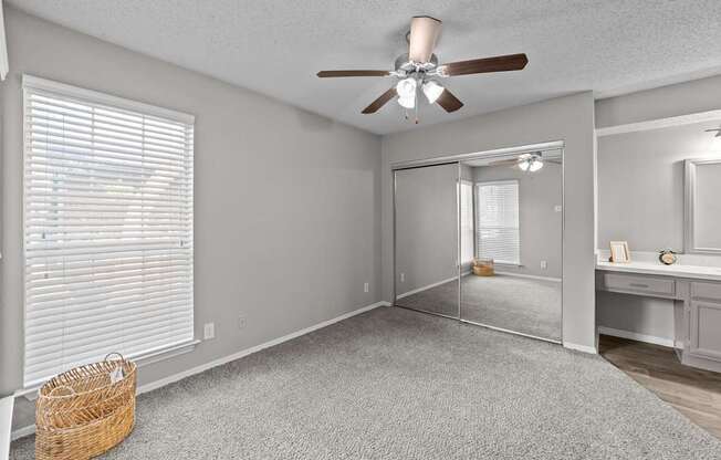 A room with a ceiling fan and a mirror on the wall.