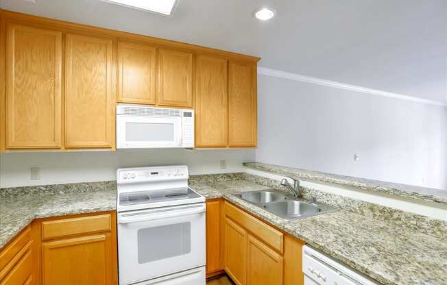 A kitchen with wooden cabinets and granite countertops.