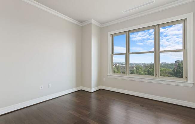 an empty living room with wood floors and a window