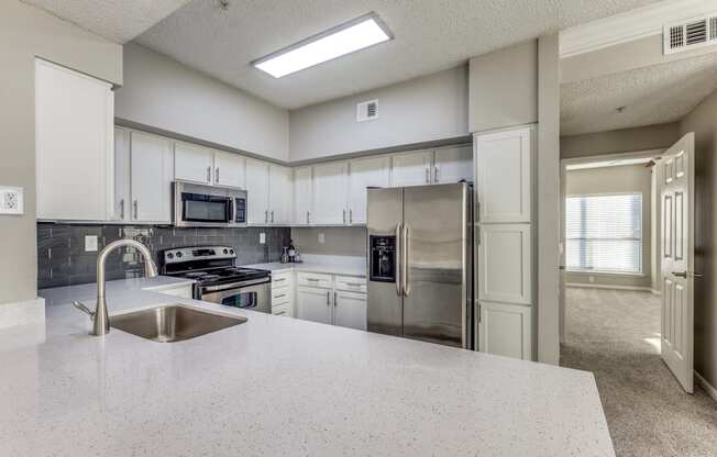 an open kitchen with stainless steel appliances and white counter tops