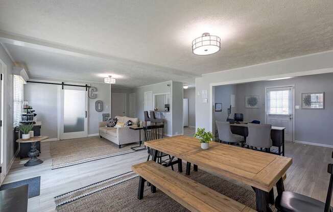 A modern open plan living and dining area with a wooden table and bench.