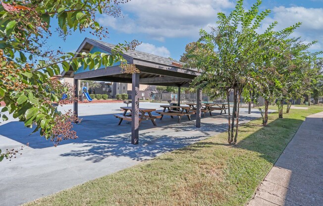 A paved pavilion with picnic tables is surrounded by trees at The Drake in Bossier City, LA