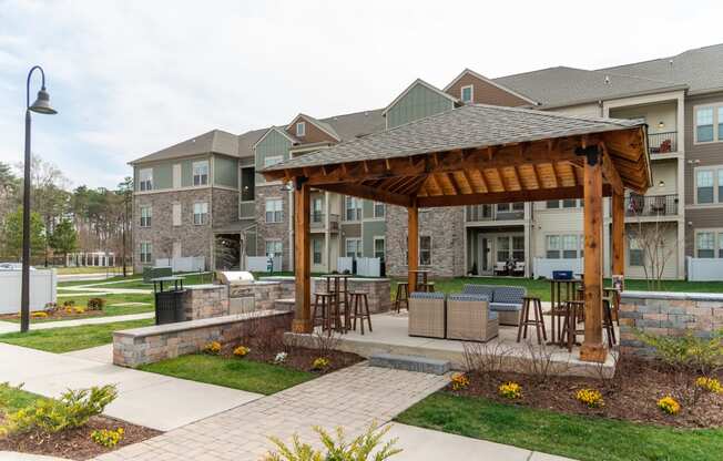 a large wooden pavilion with a stone wall in front of an apartment complex at The Whitworth, Williamsburg, VA