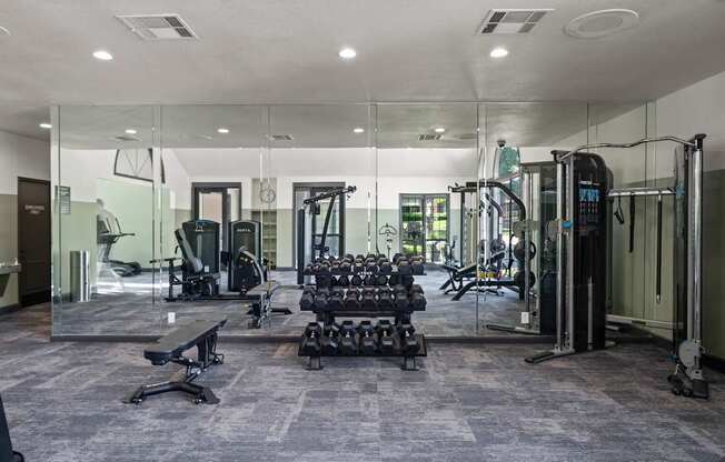 A gym with a variety of equipment including treadmills, weights, and exercise machines.