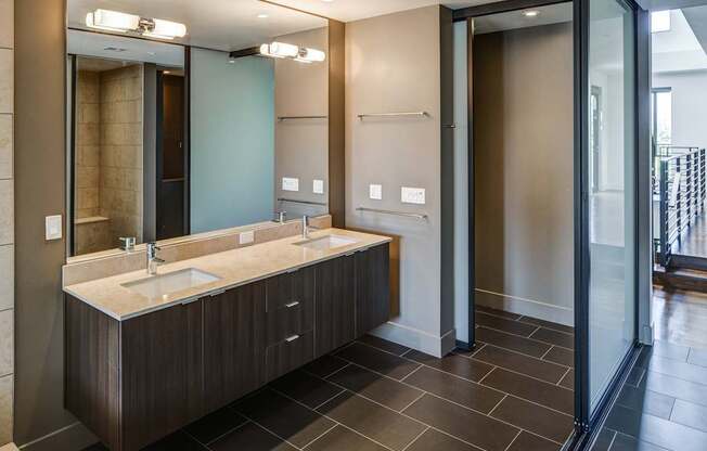 A bathroom with a double sink vanity and a walk-in shower.