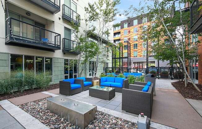 a courtyard with couches and a fire pit in front of a building