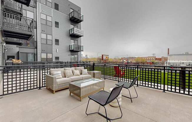 A balcony with a couch, chairs and a coffee table.