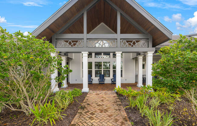 the front entrance of a white house with a brick walkway and a porch