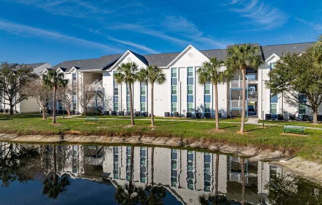 a building with palm trees in front of a body of water