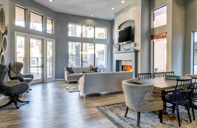 Ingleside Apartments Clubhouse with two couches, a dining table, and brown side chairs. Large windows look out to the pool