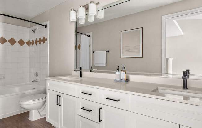 A white bathroom with a toilet, sink, and mirror.