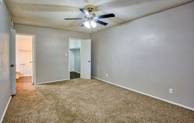 an empty living room with a ceiling fan