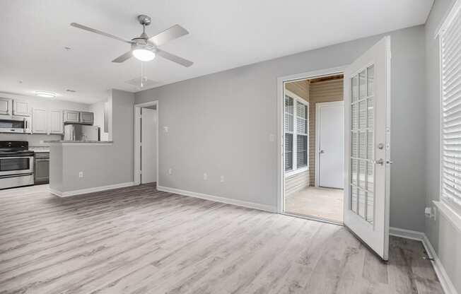 an empty living room and kitchen with a ceiling fan