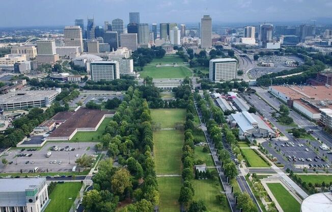 an aerial view of a park with a city skyline in the background