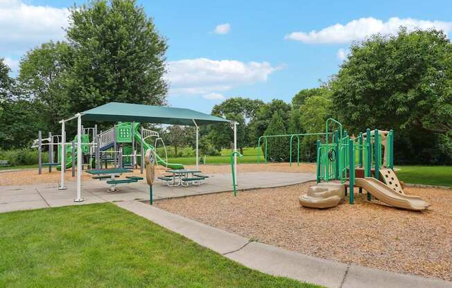 A playground with a green canopy and a slide.